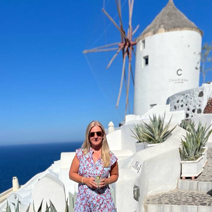 Traveler overlooking whitewashed buildings and blue-domed churches in Santorini, Greece