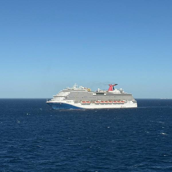 Large cruise ship sailing across open ocean on a bright day