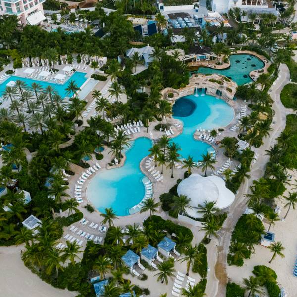 Aerial view of a luxury beachfront resort with multiple pools and palm trees
